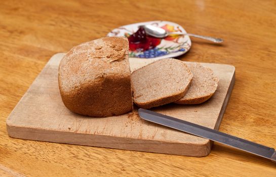 Slices of home made wheat bread on breadboard with knife