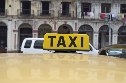 Taxi sign and reflections, old buildings on background in Havana, Cuba.