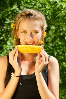 Close-up outdoor portrait of young beauty woman eating corn-cob