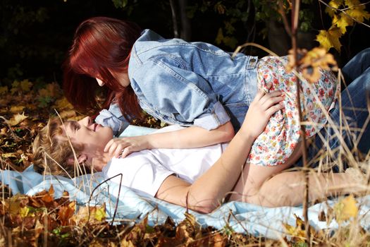 Happy young caucasian couple lying on meadow.