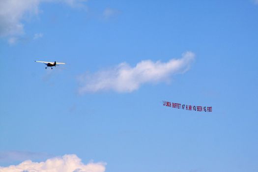 Plane dragging publicity banner through the coastline sky