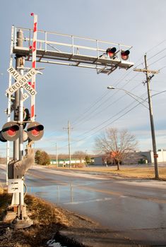 Railroad crossing sign on road under blue sky