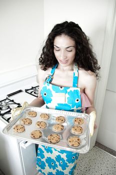 Beautiful woman baking cakes and cookies in a white home kitchen oven