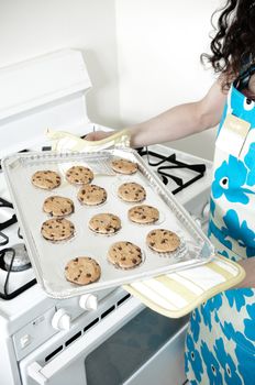 Beautiful woman baking cakes and cookies in a white home kitchen oven