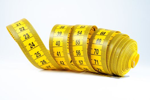 Roll of yellow measuring tape rolled up over white background