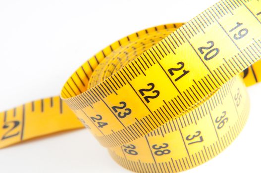 Roll of yellow measuring tape rolled up over white background