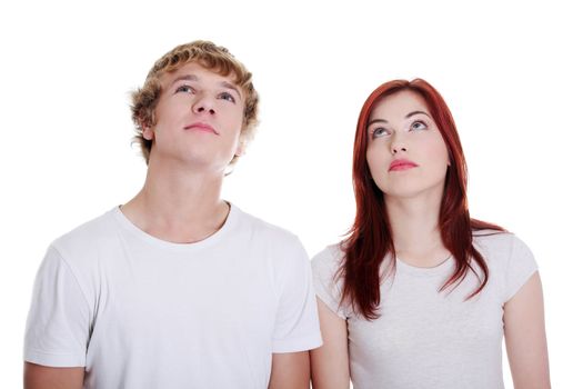 Young caucasian couple looking up against white background.