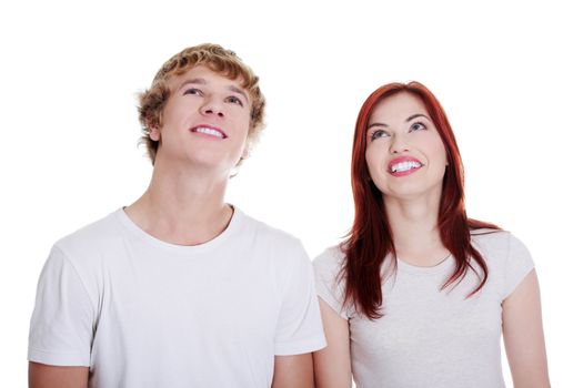 Young caucasian couple looking up against white background.