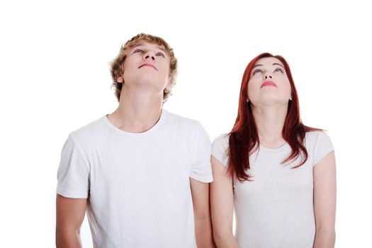 Young caucasian couple looking up against white background.