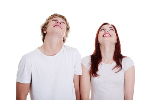 Young caucasian couple looking up against white background.