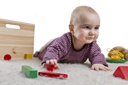 baby playing on floor with colourful toys around