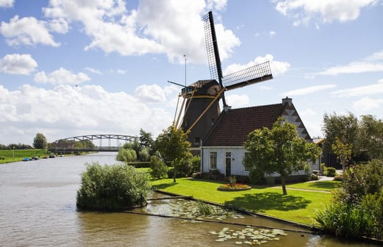 Typical Dutch landscape -  windmill, house and bridge at the waterside