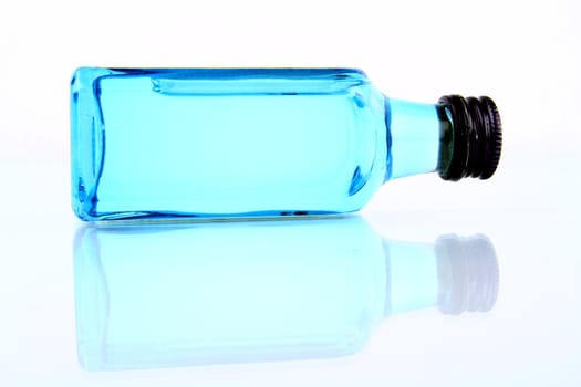 Bottle with blue liquid on white with reflection.