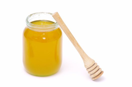 glass pot full of honey and stick isolated on white background