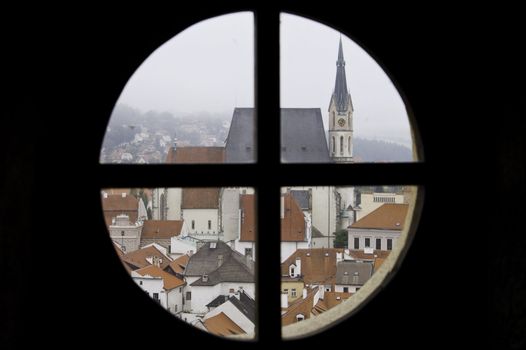 Looking through a round window out on a historic city in Cesky Krumlov, Europe.