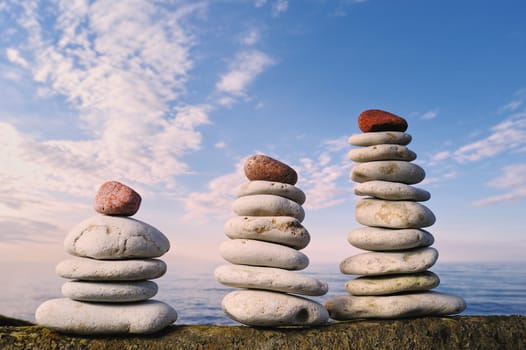 Three piles of pebbles. With red stone on the top