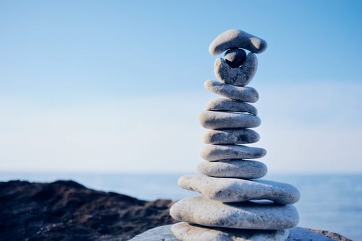 Balancing white pebbles each other on a sea boulder