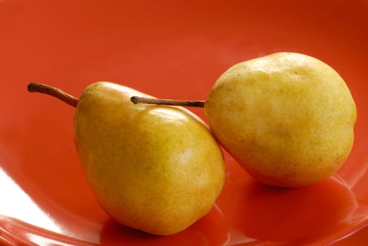 two appetizing yellow pears on red plate