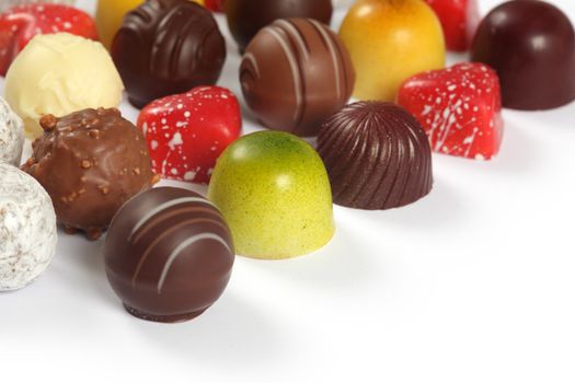 Photo of assorted truffles, pralines, and liqueur filled chocolates on white background.