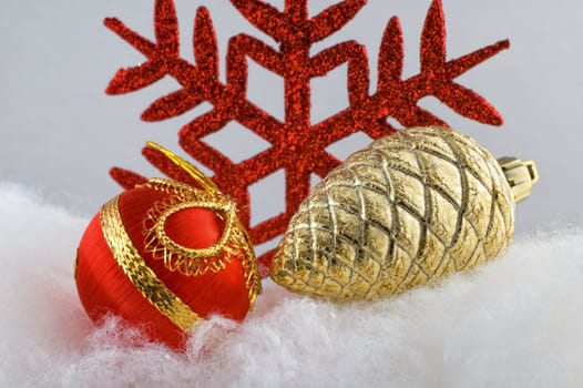 Red Christmas bauble with golden pine cone and red snowflake in the background