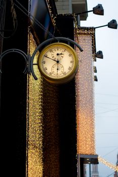 Street clock on a background of a garland