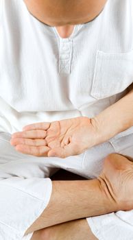 Hand of a man sitting in meditation position, palm open, looking down