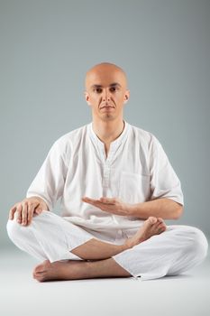 Male sitting with legs crossed, practicing thai meditating, looking at camera