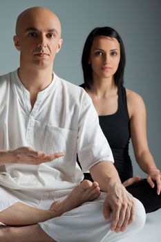 Man in white and woman in black doing yoga exercise, meditation