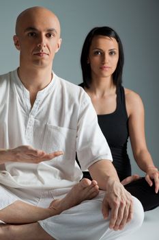 Man in white and woman in black doing yoga exercise, male on focus