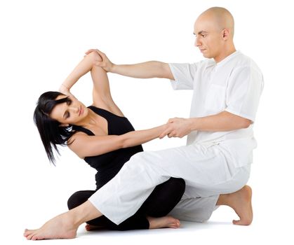 Young female sitting and receiving traditional thai arm stretching massage by therapist, isolated on white