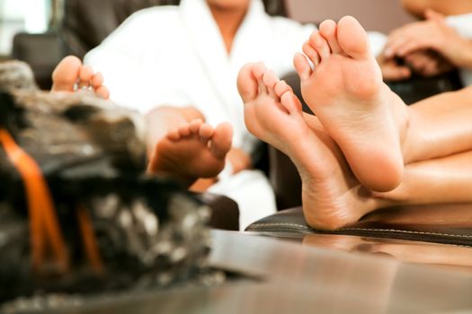 Two female friends relaxing behind fireplace, close-up on feet