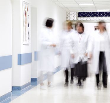 blurred figures of doctors and nurses walking in a hospital corridor