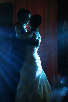 The first dance of the groom and the bride in blue beams                         