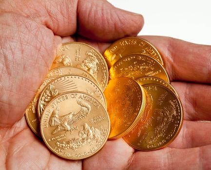 Gold Eagle one ounce coins in a stack in the palm of a hand