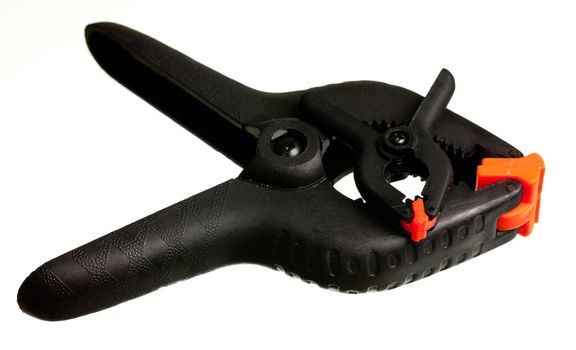 Two black spring clips with orange jaws used to hold small objects together as a clamp with a small one sitting on the larger one