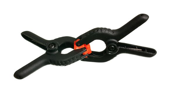 Two black spring clips with orange jaws used to hold small objects together as a clamp with a small one gripping another small one