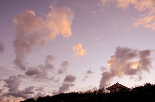 Small wooden house at the seaside on a background of cloudy sky.