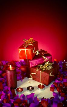 Christmas gifts and candles over red background