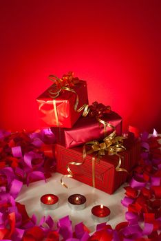 Christmas gifts and candles over red background