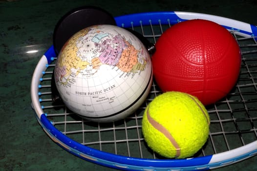 globe, tennis ball, basketball on tennis racket