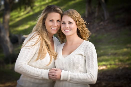 Pretty Mother and Daughter Portrait Hugging in the Park on a Fall Day.