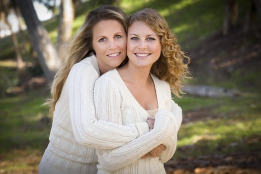 Pretty Mother and Daughter Portrait Hugging in the Park on a Fall Day.