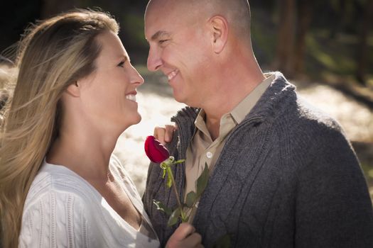 Attractive Young Couple Wearing Sweaters with a Rose in the Park.