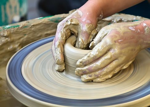 A pair of hands work on pottery 