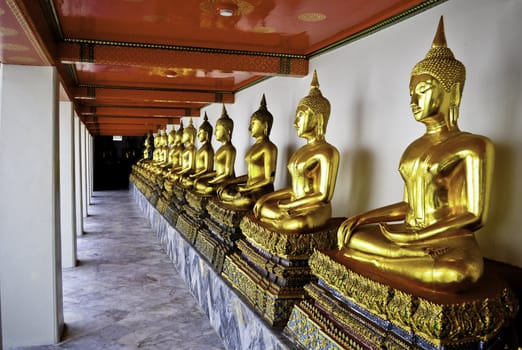 A row of gold Thai buddhas in Bangkok, Thailand