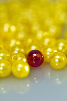 Close up of a red bead surrounded by yellow beads with shallow DOF, with mirror image in portrait orientation