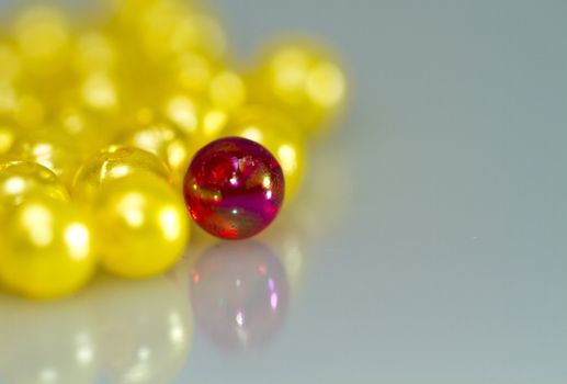 Close up of a red bead in front of yellow beads with shallow DOF, with mirror image in landscape orientation