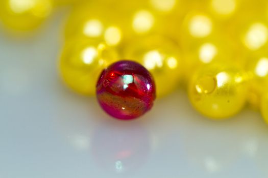 Close up of a red bead in front of yellow beads with shallow DOF, with mirror image in landscape orientation