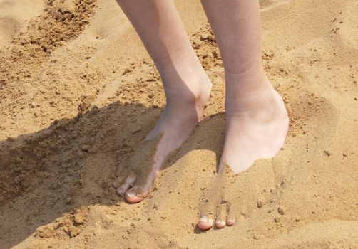 A boys feet partly buried in sand