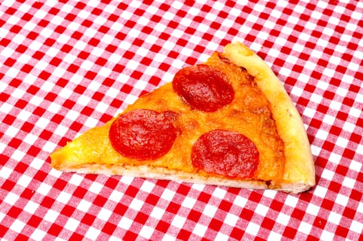 Pepperoni pizza slice on red gingham tablecloth.